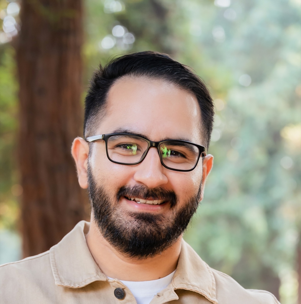 Bryan Cuevas smiling outdoors in a forested park